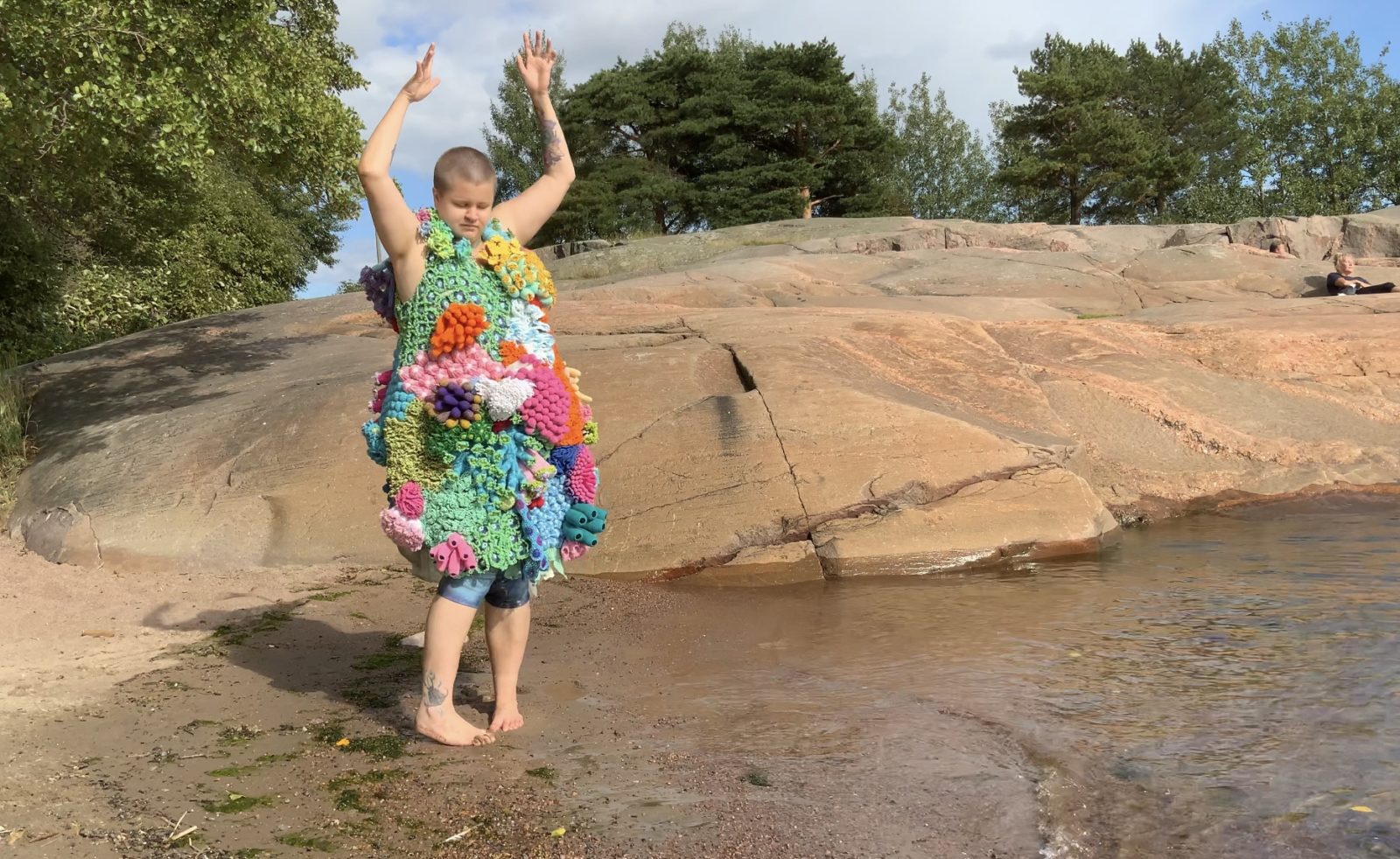 Maria Tani standing bare feet on a beach wearing the Breathing reef -artwork.