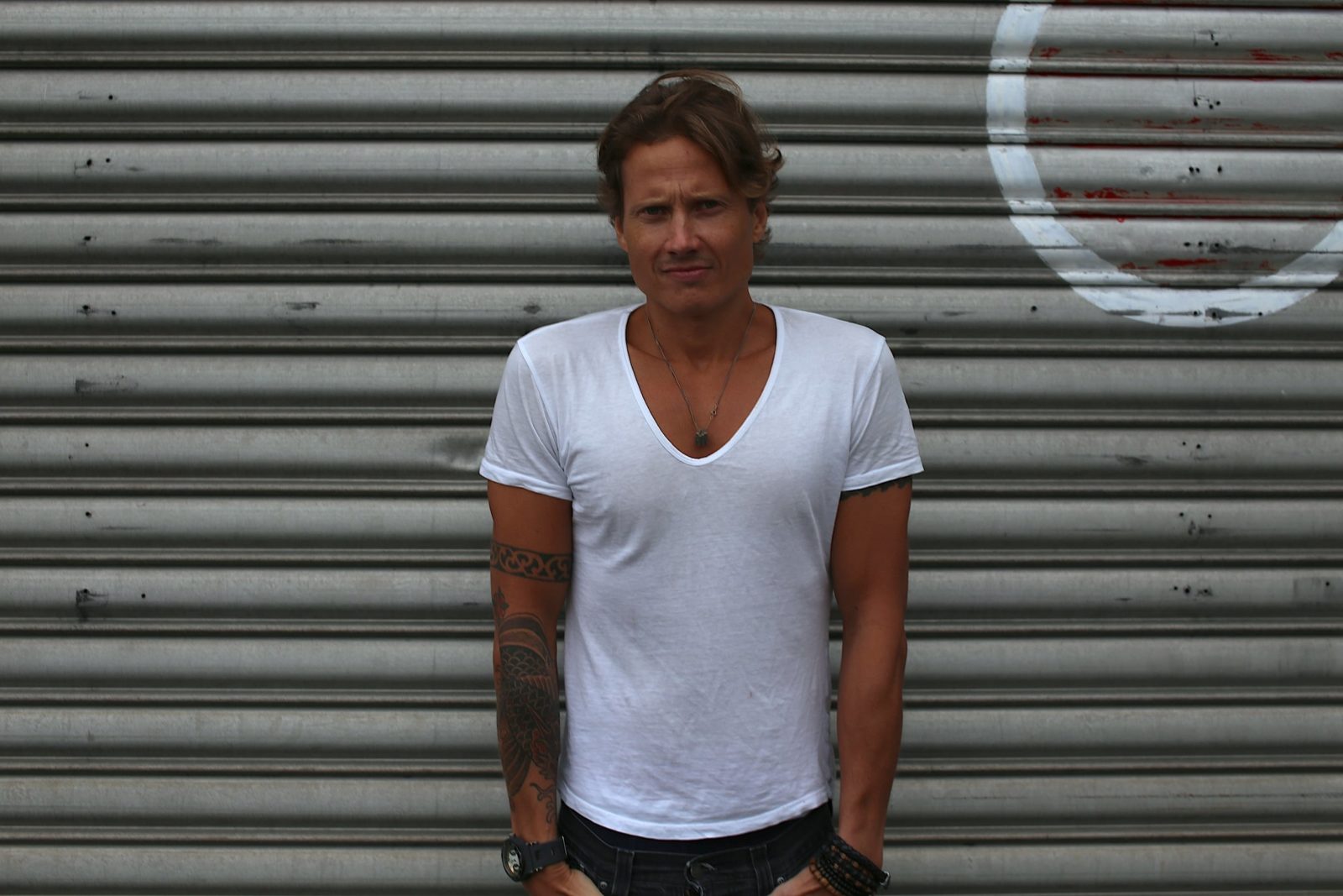 Aleksi Tuomarila standing in front of a garage door in a white t-shirt.