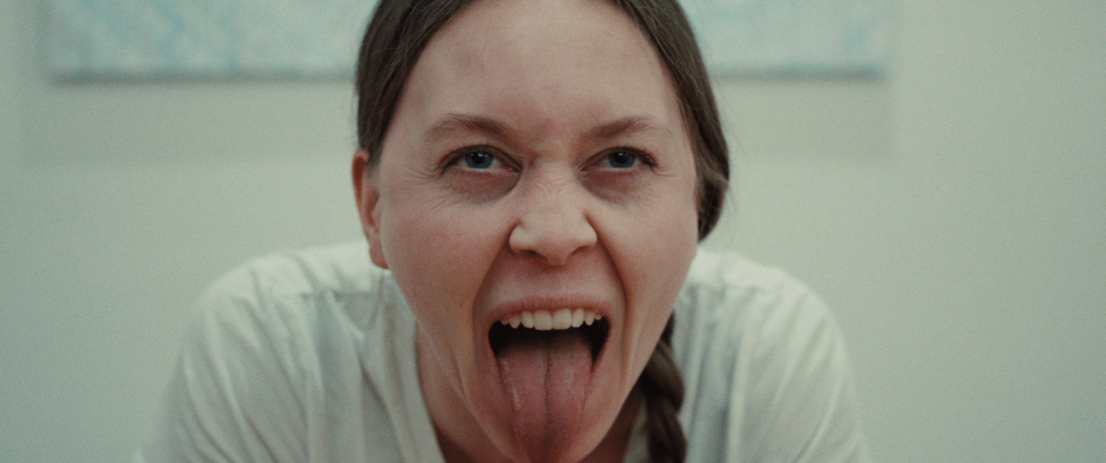 Extrait du film BAND par Álfrún Örnólfsdóttir avec une femme portant un tee-shirt blanc, avec le regard porté sur la caméra et qui tire la langue.