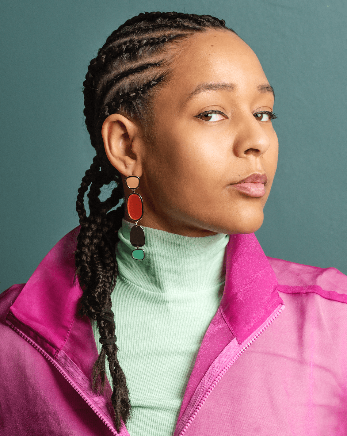 Portrait de Sonya Lindfors facing the camera wearing cornrows and a pink jacket.